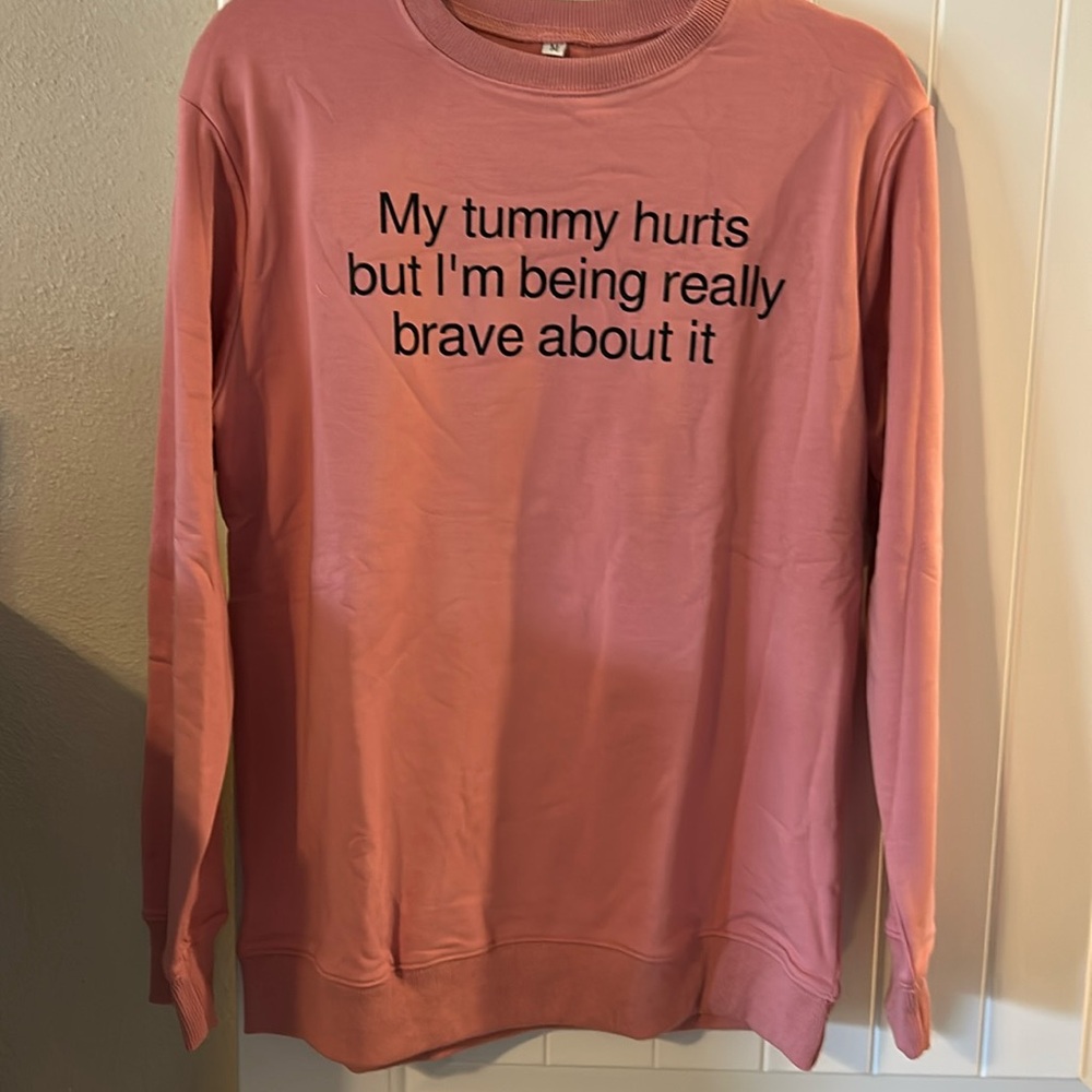 pink crewneck sweatshirt with writing on front.